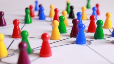 Small plastic coloured game pieces on a board with nodes to represent a team of people collaborating